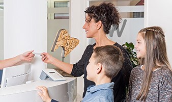 Happy family paying a dental receptionist