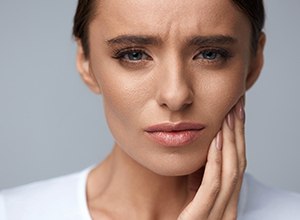 sad woman in dental pain holding cheek