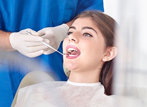 dentist looking at woman's teeth with a dental mirror