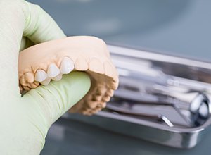 hand holding tooth model with dental bridge