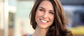 girl with brown hair and straight teeth smiling